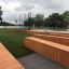 Multiarena Wooden outdoor playground with wooden benches and structures near a lakeside park.