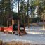 Locomotive with cars train playhouse on sandy playground in forest.