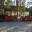 Playground Locomotive with cars train playhouse in a sandy area surrounded by trees.