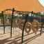 Caterpillar climbing net playground equipment under a sunshade.