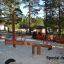 Wooden Nature Seesaw in a playground surrounded by trees.