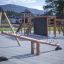 Wooden Nature Seesaw on modern playground with climbing structures in the background.