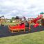 Locomotive train playhouse on a playground with swings and slides.