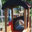 Locomotive train playhouse with slide and tunnel feature in a wooded area.