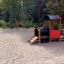 Locomotive train playhouse in outdoor playground with swing set in background.