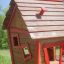 Wooden playhouse with red trim in a grassy area - Anna's Playhouse.