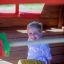 Child playing inside Anna's Playhouse made of wood.