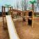 Jungle castle with slide on playground with trees in background.