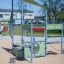 Modern Pluto playground equipment for kids installed in a sandy playground area.