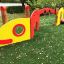 Baby Caterpillar wooden playhouse in red and yellow with a circular window and small climbing platfo