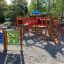 Race Track Board children's playground set with slides and climbing structures in a park.