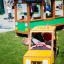 Children playing in a toy bus and a taxi at a playground.
