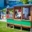 Children playing in a wooden bus-shaped playground structure.