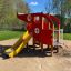 Red Helicopter playground structure with yellow slide in a sandpit.