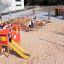 Children playing on Helicopter-themed playground equipment with a slide at a sandy playground.
