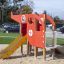 Red outdoor playground helicopter playset with slide and climbing net.