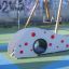 Playground equipment Dottie I single slide with tunnel and red climbing grips.