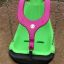 All Access Seat - inclusive playground swing with green and pink colors on sandy ground