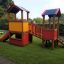 Knight's Castle playhouse with slide in a garden.