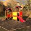 Knight's Castle playhouse with slide in a playground setting.