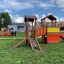 Knight's Castle playhouse with slide in playground