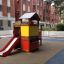 Children's Knight's Castle playhouse with slide in a playground.