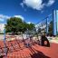 Copernicus steel structure climbing playground equipment on red safety surface under blue sky.