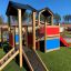 Tower playhouse with slide in a playground area with green artificial grass