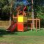 Tower playhouse with slide in a playground surrounded by trees