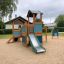 Tower playhouse with slide on a sandy playground.