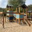 Tower playhouse with slide in a sandy playground.