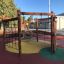 Sequoia wooden playhouse with climbing net and tire swing on playground.