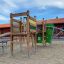 El Dorado wooden playhouse with slide and climbing frame in a playground.