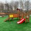 Outdoor playground equipment: Fortress playhouse with slide on artificial grass.