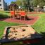 Fortress playhouse with slide in a playground with a sandbox and swingset
