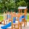 Wooden Fortress playhouse with slide, blue accents, and climbing features in a playground.