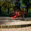 Fortress playhouse with slide in a sand playground surrounded by trees