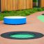 Round trampoline (100 cm) embedded in playground surface with green jumping mat and black border.