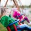 Two children playing on Double Baby Swing in the park.