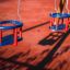 Double Baby Swing on a playground with red and blue seats on chains.