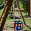 Double Baby Swing in a colorful playground with wooden frame.