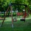 A wooden Double Swing set on a green playground.