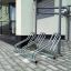 Cross 3 modern steel bicycle rack on paved ground near building entrance
