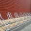 Bicycle rack Cross 10 next to a brick wall.