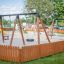 Double Swing playground equipment in a fenced play area with other playground structures visible.