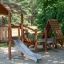 Galapagos wooden playhouse with slide in a park setting