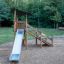 Elbrus wooden playhouse with slide on a playground surrounded by trees