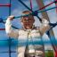Child climbing on Autan climbing net playground equipment in outdoor setting