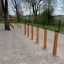 Agility Weave Poles set up outdoors on a gravel surface with trees in the background.