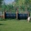 Two dogs near an Agility Tunnel in a fenced grassy area.